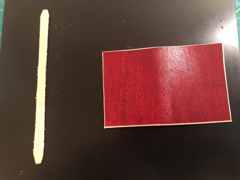 本の形のキーホルダー用に切り取った赤い革とストラップ用のヌメ革